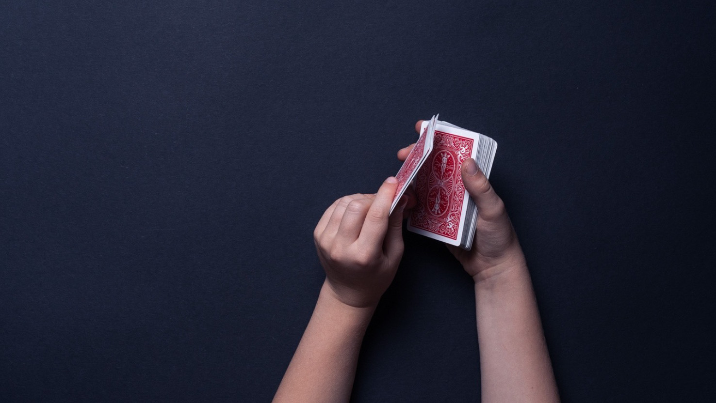 Ein Kind legt vier Asse verdeckt auf den Kartenstapel.
