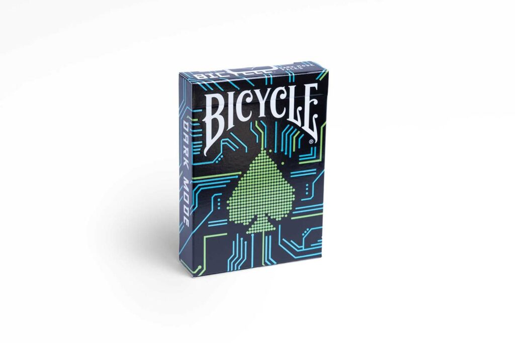 Eine Bicycle Creatives Dark Mode Kartenschachtel steht mit sichtbarer Vorderseite vor einem weißem Hintergrund.