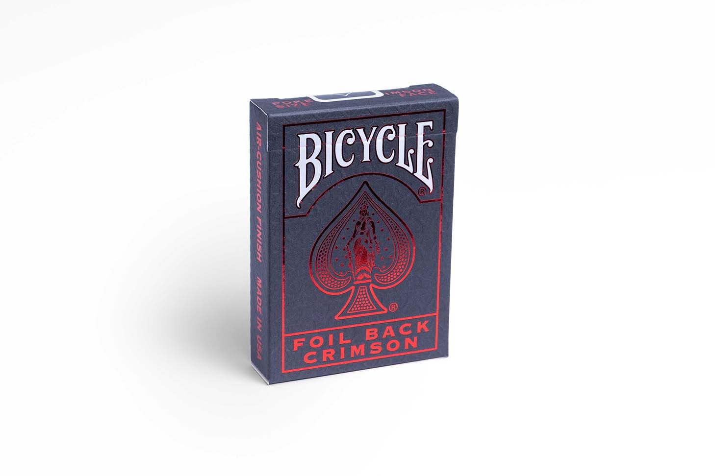 Eine Bicycle Ultimates Foil Back Crimson Red Kartenschachtel steht mit sichtbarer Vorderseite vor einem weißem Hintergrund.