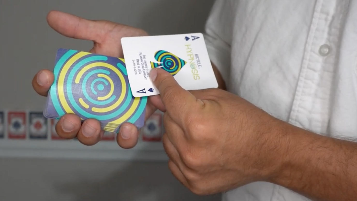 Das Beitragsbild für das Tutorial Video für den Arrow Spin Zaubertrick zeigt ein Kartendecktvor dem ein Pik Ass gehalten wird.