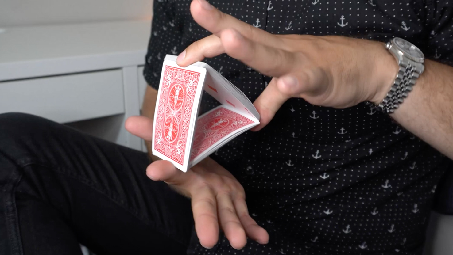 Das Beitragsbild für das Tutorial Video für den Trick Chip Zaubertrick zeigt eine Person die ein Dreieck aus Bicycle Karten in den Händen hält.