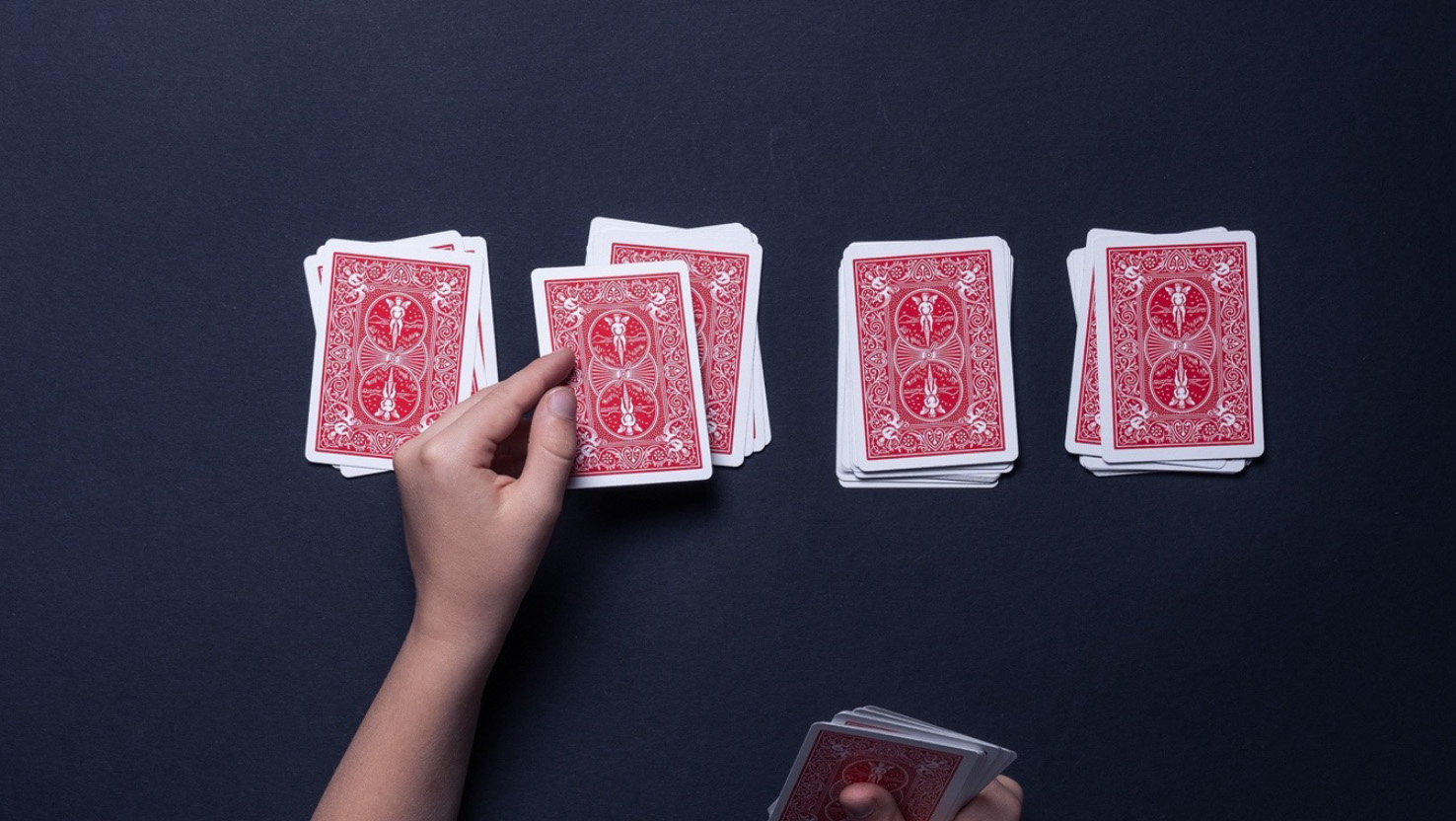 Bei einem Kartentrick legt ein Kind vier Kartenstapel.