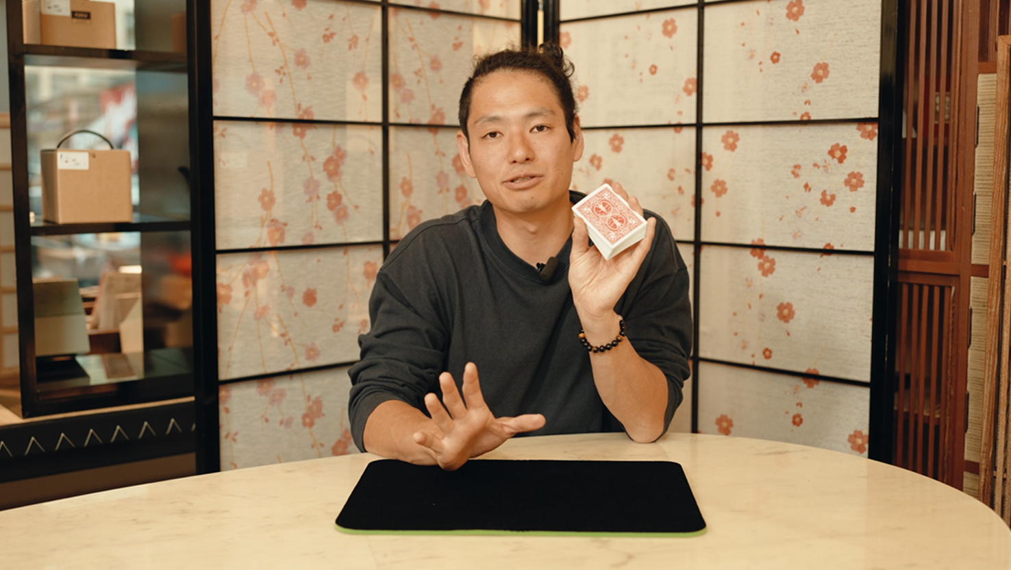 Das Beitragsbild für das Tutorial Video für diesen Pinky Break Zaubertrick zeigt den Zauberkünstler Yuta, der ein Kartendeckt in der Hand hält.