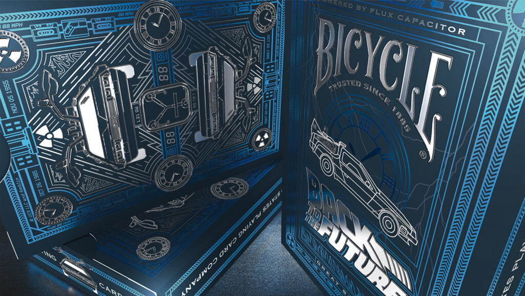 Die Detailaufnahme zeigt drei Schachteln des Bicycle Creativey Back to the future Kartenspiels. Die Schachteln sind mit Silberfolie veredelt und glänzen. Marty McFly, Bicycle Spielkarten
