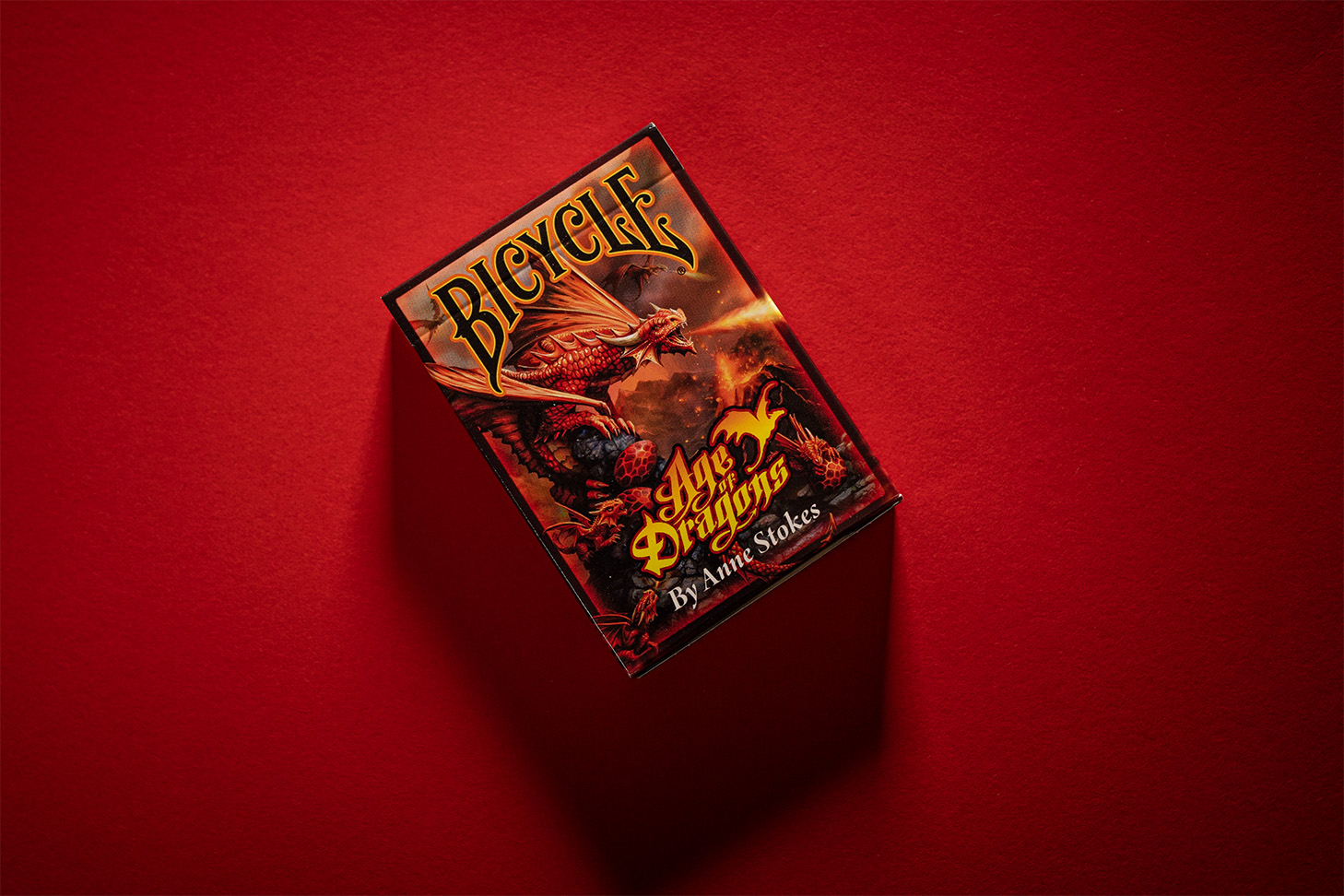 Die Bicycle® Age of Dragons Kartenschachtel liegt aus der Vogelperspektive sichtbar auf einem roten Hintergrund. Das erstklassige Design der Spielkarten zeigt majestätische Drachen in voller Pracht und eignet sich perfekt für gute Kartenspiele, Zauberkarten und Magie. Holen Sie sich jetzt diese exklusiven Spielkarten für unvergessliche Spieleabende!
