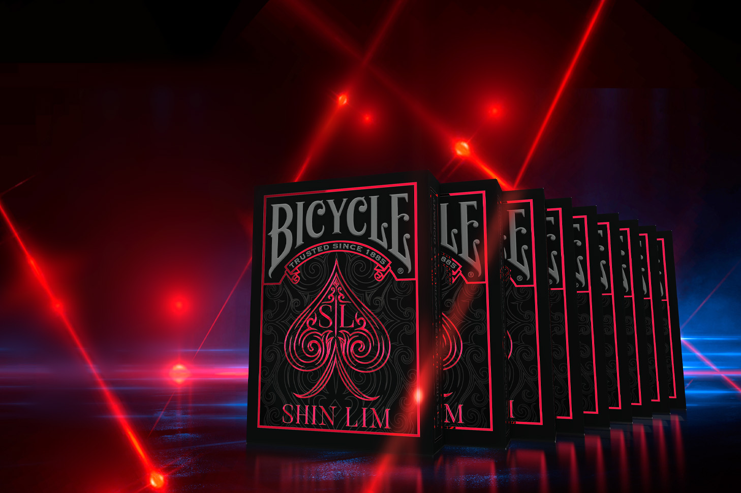 Mehrere Bicycle Creatives Shin Lim Kartenschachteln stehen aufgereiht voreinander mit sichtbaren Vorderseiten. Der Hintergrund ist unscharf und atmosphärisch.