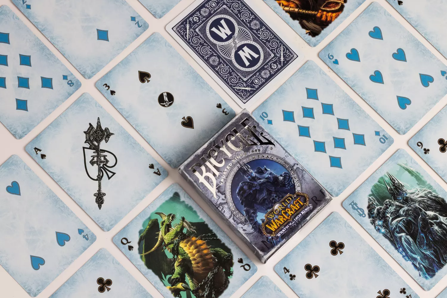 Eine Bicycle Creatives Bicycle World of Warcraft Wrath of the Lich King Kartenschachtel liegt auf einem weißem Hintergrund, neben der Schachtel liegen die Karten aus dem Deck.