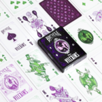 Die Karten einer Bicycle Creatives Bicycle Disney Villains purple lila Kartenschachtel liegen ausgebreitet auf einer Fläche sodass man verschieden Vorderseiten und Rückseiten und die Schachtel sehen kann.