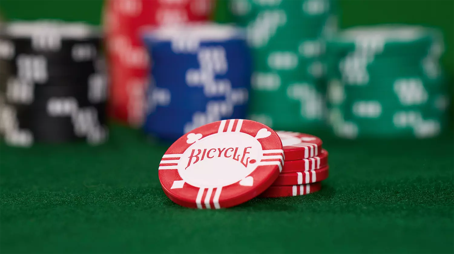 Die Bicycle originals Poker Chips liegen ausgepackt auf einem grünen Pokertisch.