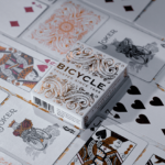 Eine Bicycle Creatives Botanica Kartenschachtel liegt zwischen Karten aus dem Deck, es sind Vorderseiten und Rückseiten zu sehen.