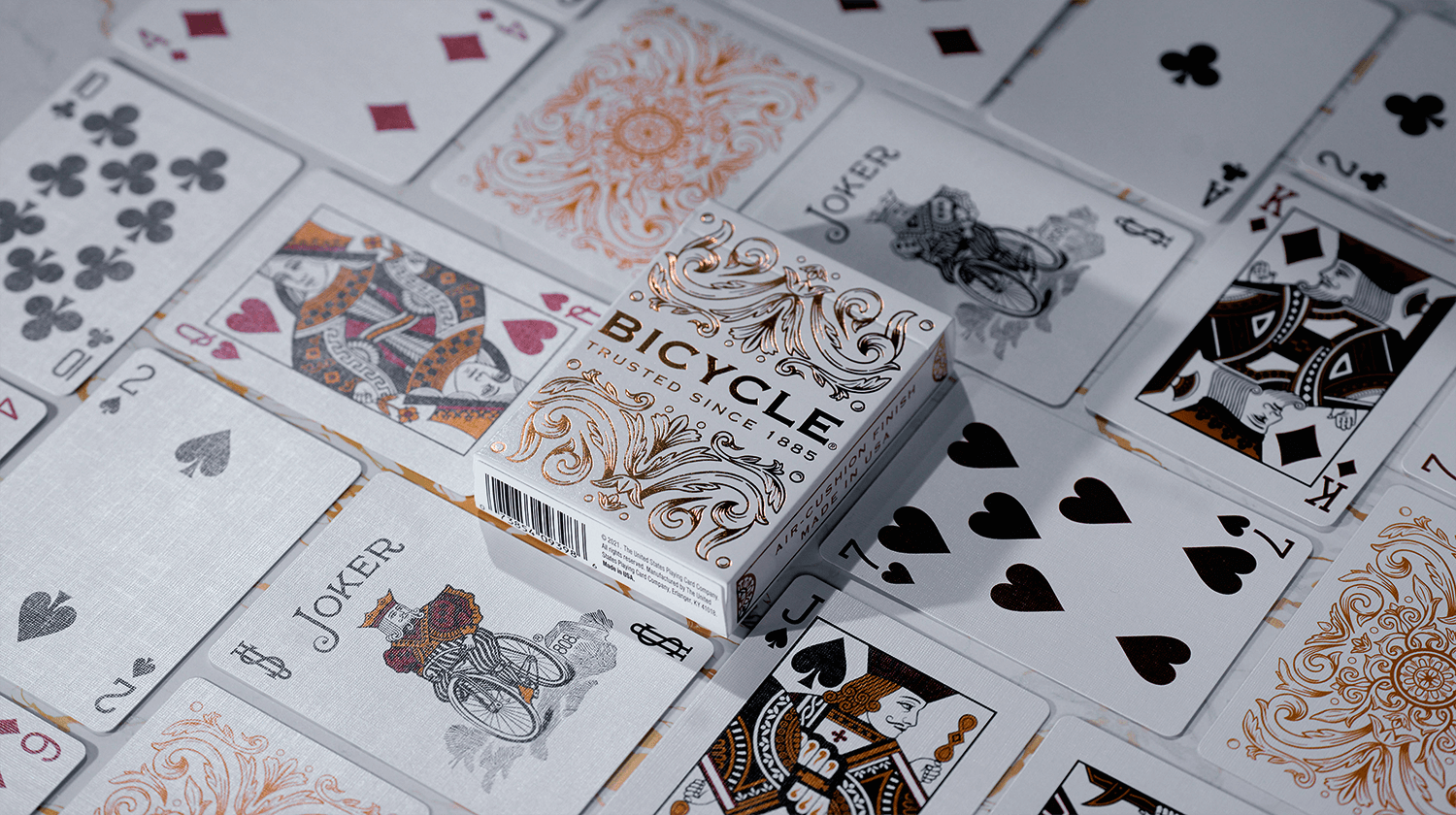 Eine Bicycle Creatives Botanica Kartenschachtel liegt zwischen Karten aus dem Deck, es sind Vorderseiten und Rückseiten zu sehen.