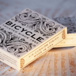Eine Bicycle Creatives Botanica Kartenschachtel liegt auf einem Hintergrund aus Kartenrückseiten, die Schachtel liegt schräg auf einer weiteren Schachtel.