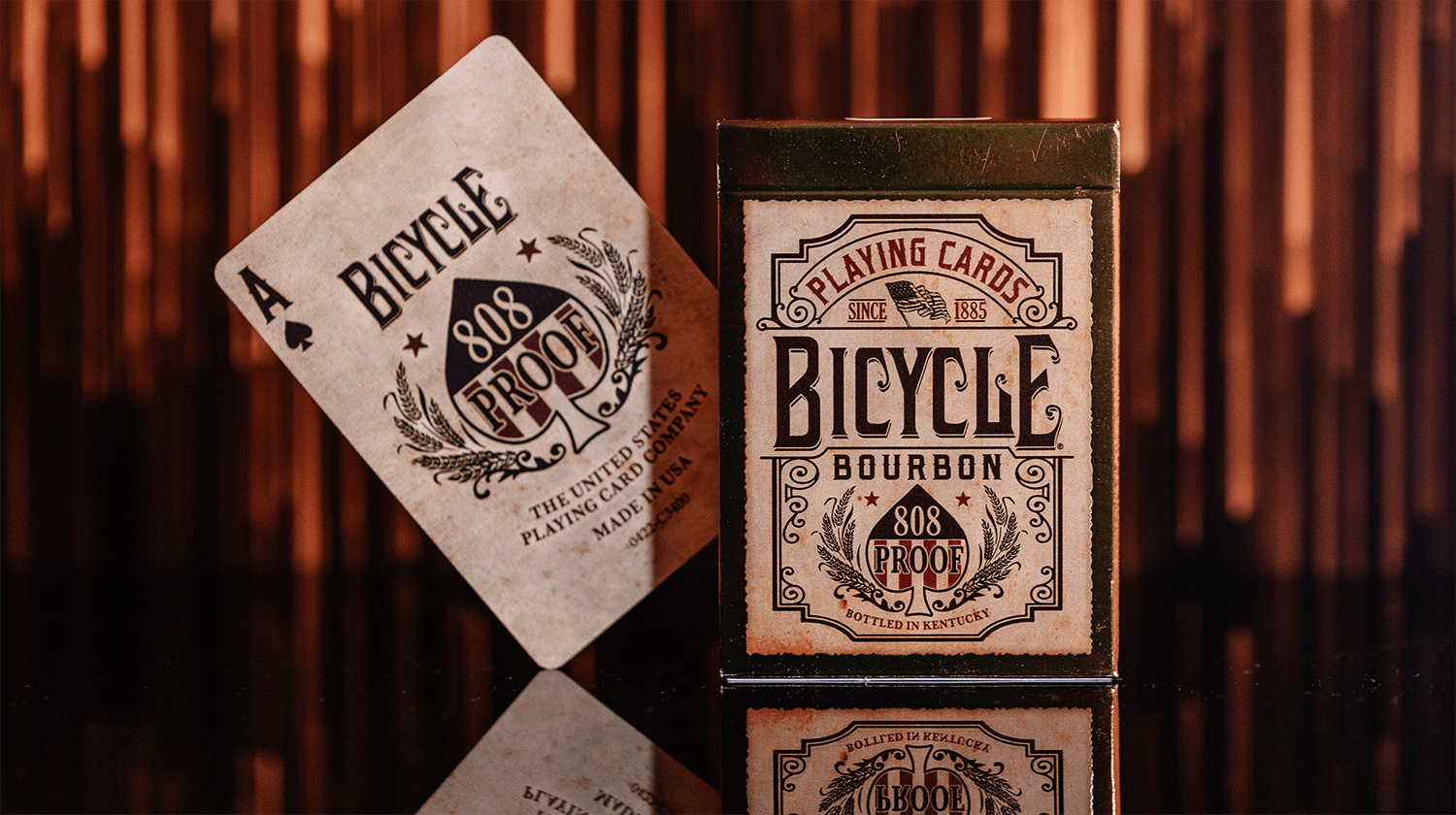 Von einer Bicycle Creatives Bourbon Kartenschachtel ist die Vorderseite zu sehen, daneben ist die Vorderseite einer Karte zu sehen.