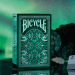 Eine Bicycle Creatives Jacquard Kartenschachtel steht mit sichtbarer Vorderseite vor einem grünen Hintergrund.