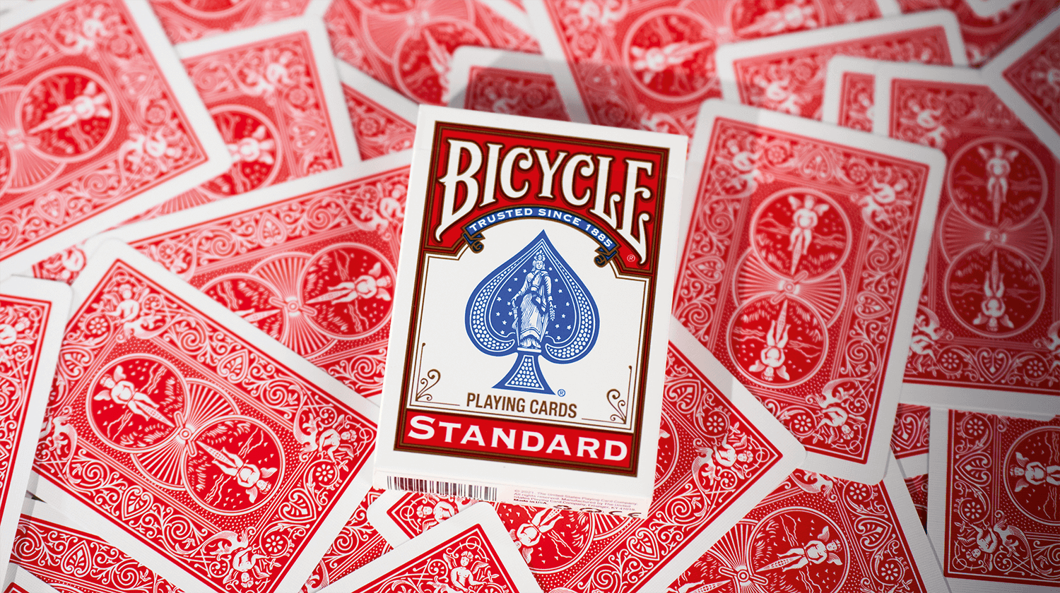 Eine Bicycle Trick Deck Double Back Red Rot Kartenschachtel liegt auf ausgebreiteten Kartenrückseiten.