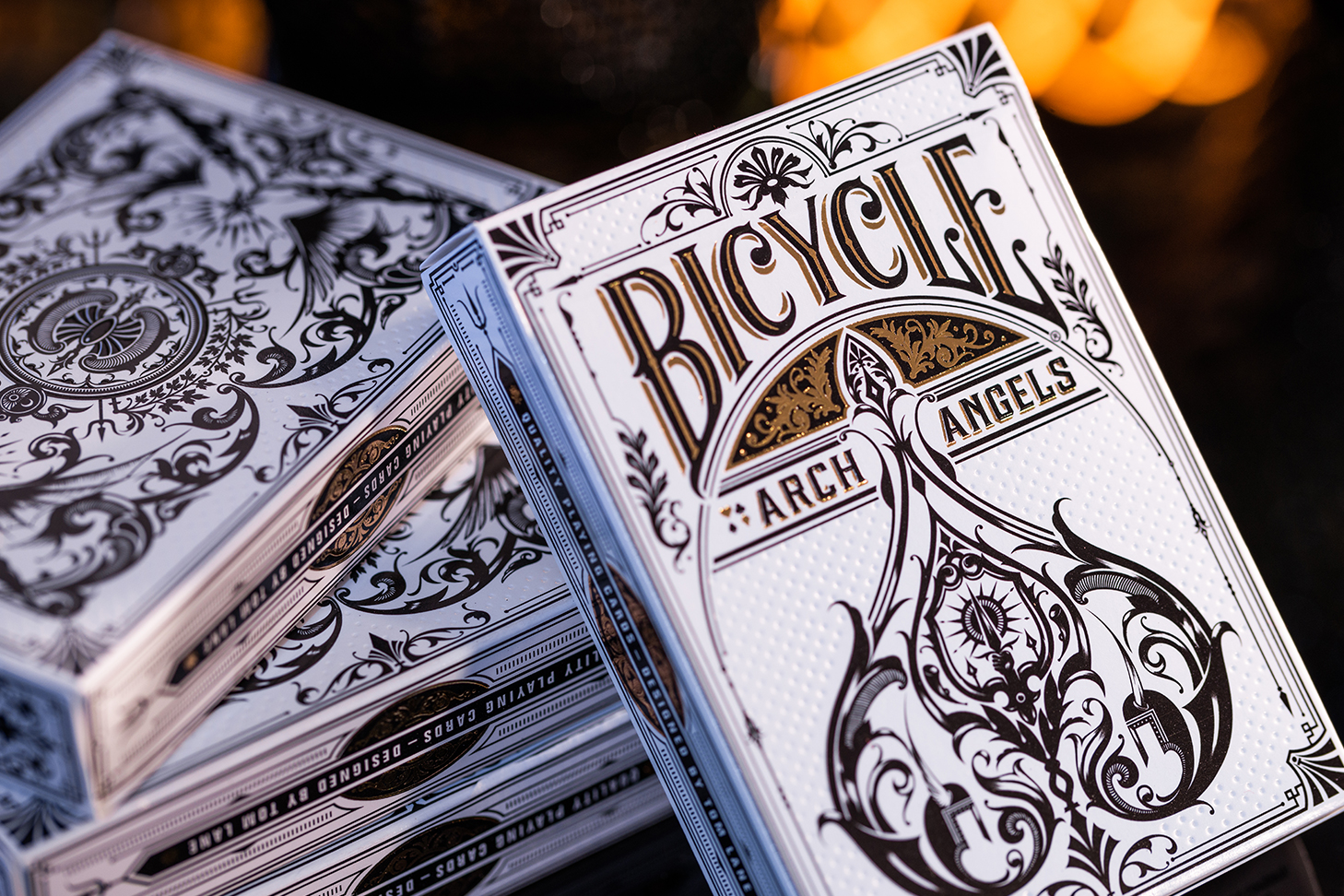 Eine Bicycle Creatives Archangels Kartenschachtel lehnt mit sichtbarer Vorderseite an einem Stapel Kartenschachteln mit sichtbarer Rückseite.