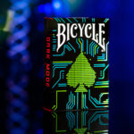 Eine Bicycle Creatives Dark Mode Kartenschachtel steht mit sichtbarer Vorderseite vor einem atmosphärischem und unscharfem Hintegrund.