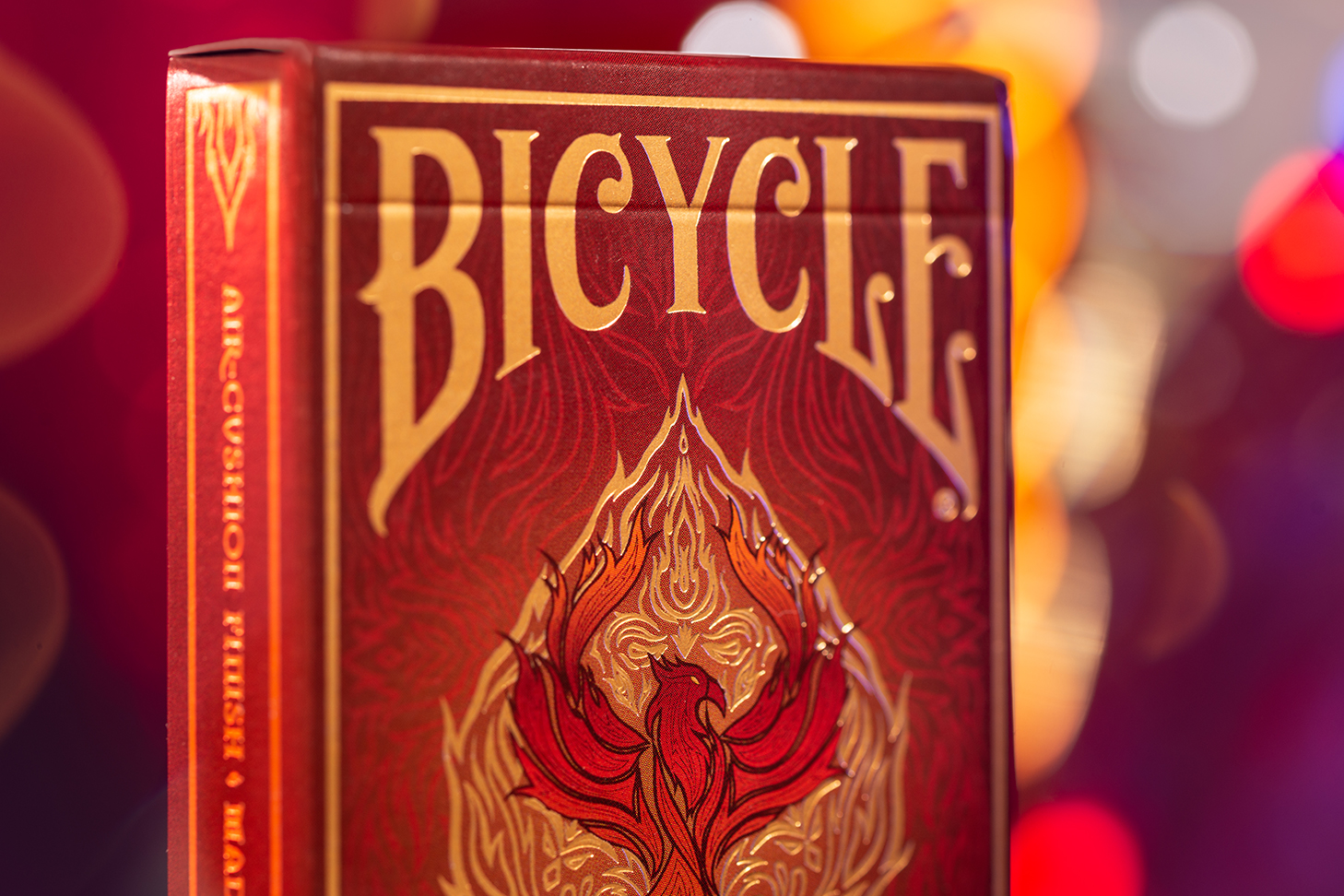 Eine Bicycle Creatives Fyrebird Kartenschachtel steht mit sichtbarer Vorderseite vor einem unscharfem Hintergrund. Das Bicycle Logo und die Fyrebird Illustration sind sichtbar.