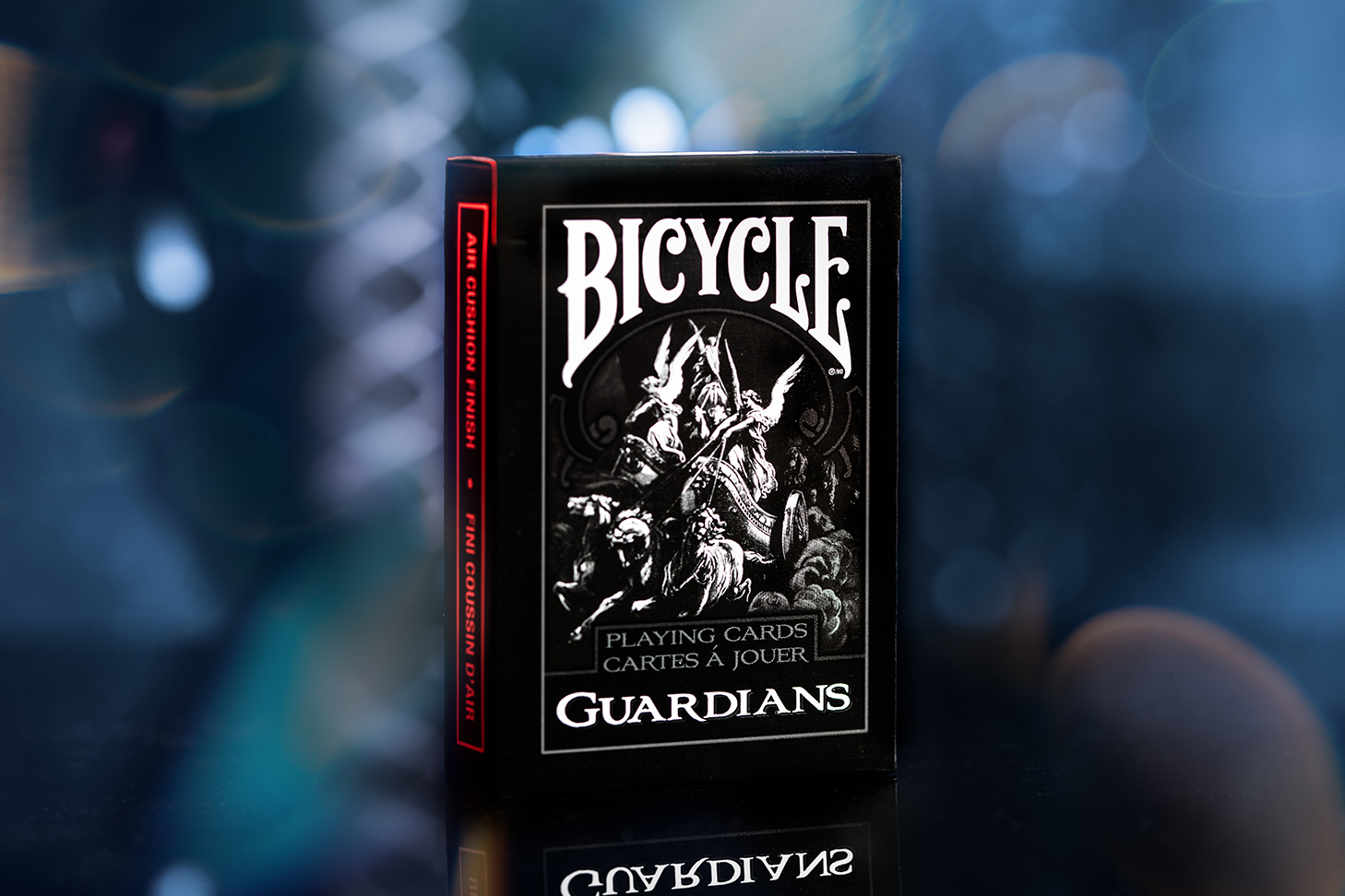 Eine Bicycle Creatives Guardians Kartenschachtel steht mit sichtbarer Vorderseite vor einem unscharfem Hintergrund.