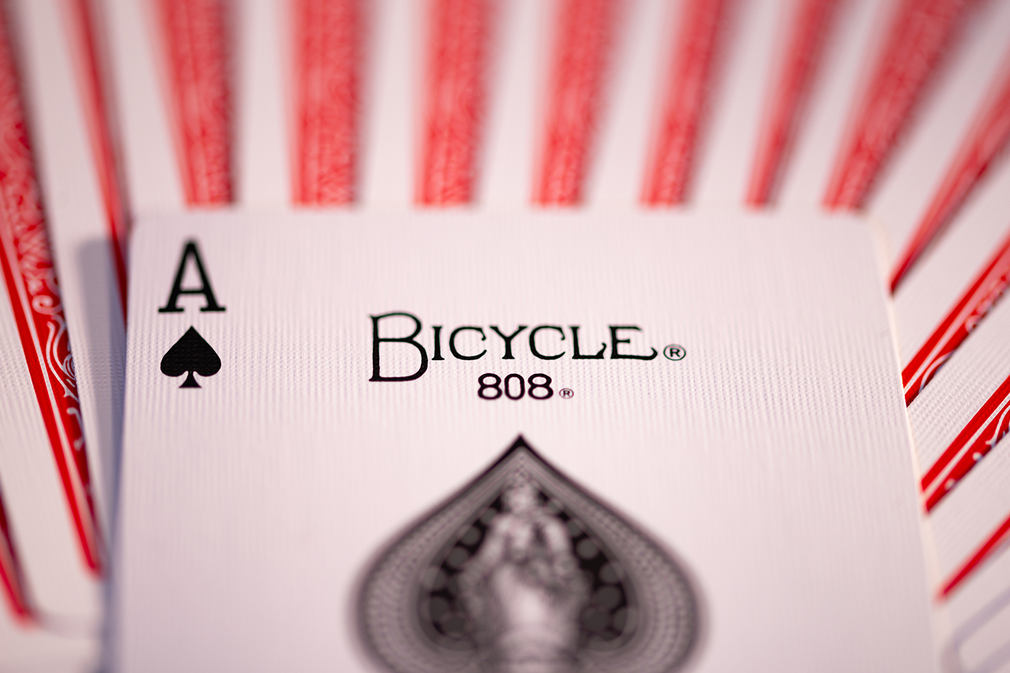 Die Pik Ass Bicycle Originals Gold Standard Rot Karte liegt auf einem Kartenstapel mit sichtbaren Rückseiten.