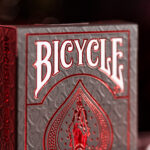 Die Bicycle Ultimates Foil Back Crimson Red Kartenschachtel steht mit angeschnittener sichtbarer Vorderseite vor einem dunklem Hintergrund und wird rot beleuchtet.