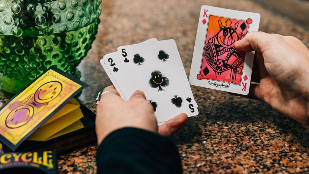 Person hält Smiley Karten Deck und Kartenschachtel