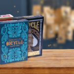 Die Bicycle Creatives Spielkarten Sea King und Architectural wonders of the world, so wie das Bicycle Originals Gold Standard Rot Deck stehen vor einem Adventskanlender auf einem Untergrund aus Holz und eignen sich hervorragend dazu einen Adventskalender selbst zu befüllen.