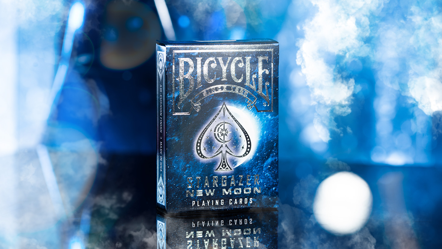 Ein Bicycle Creatives Stargazer New Moon Kartenspiel steht mit sichtbarer Vorderseite vor einem blauem und unscharfem Hintergrund.