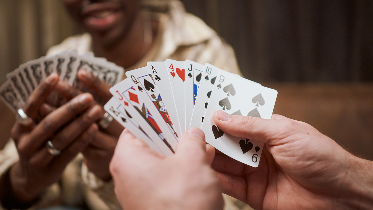 Freunde spielen Karten und rätseln über die Spielkarten-Symbole und ihre Bedeutung